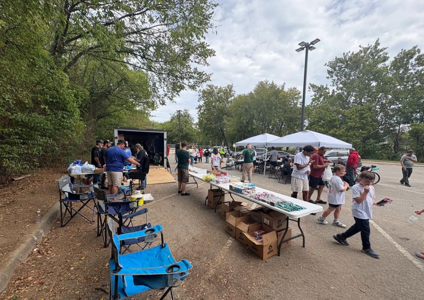 Supply tables, canopies and the outreach trailer set up across a parking lot