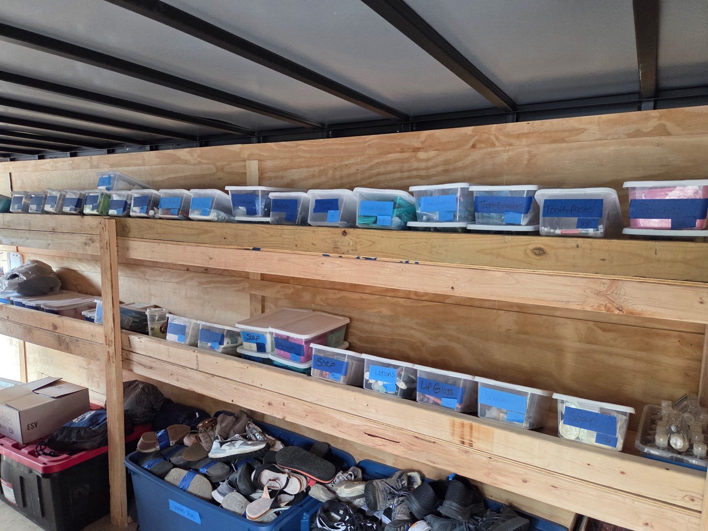 Shelves of labeled bins and donated shoes stocked inside the trailer